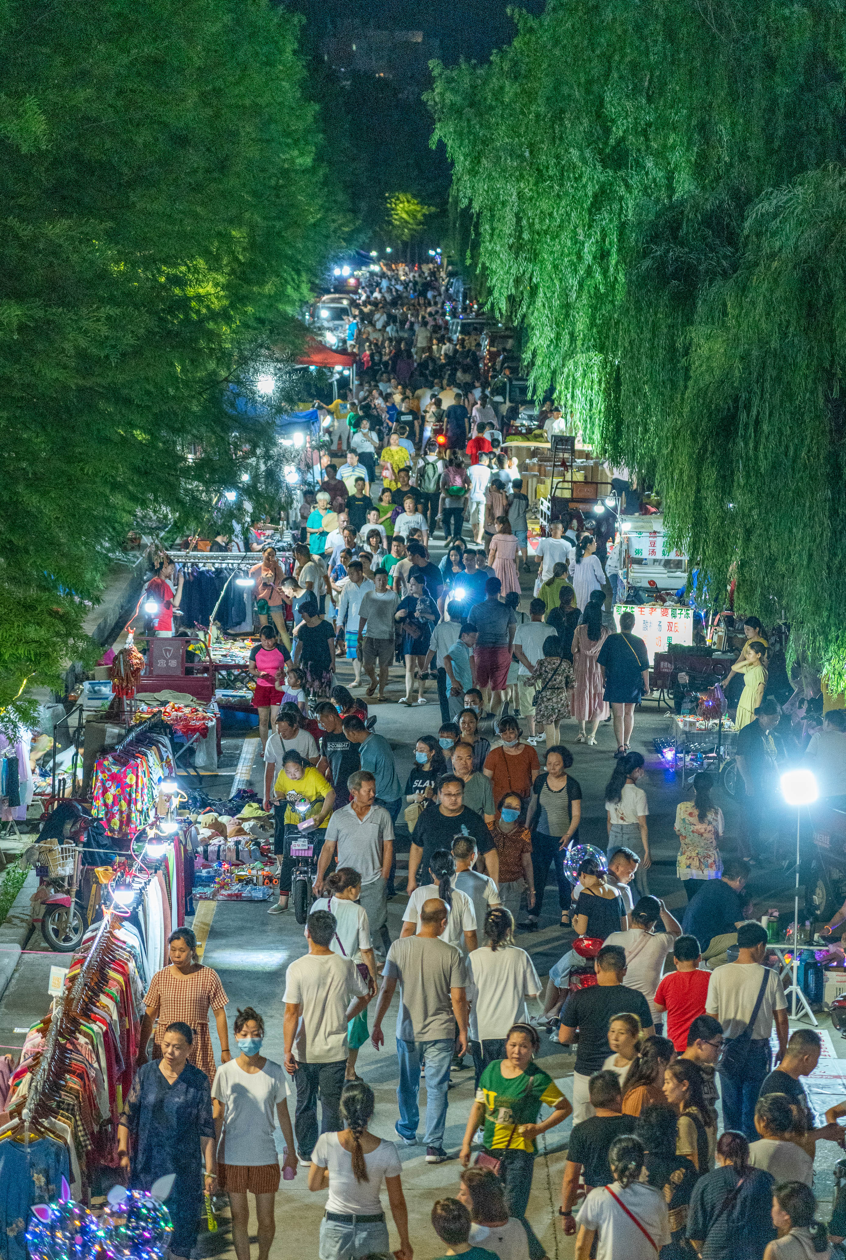 俯瞰信阳市浉河步行道夜市摊点桥洞下人流如织客户正认真挑选商品一位